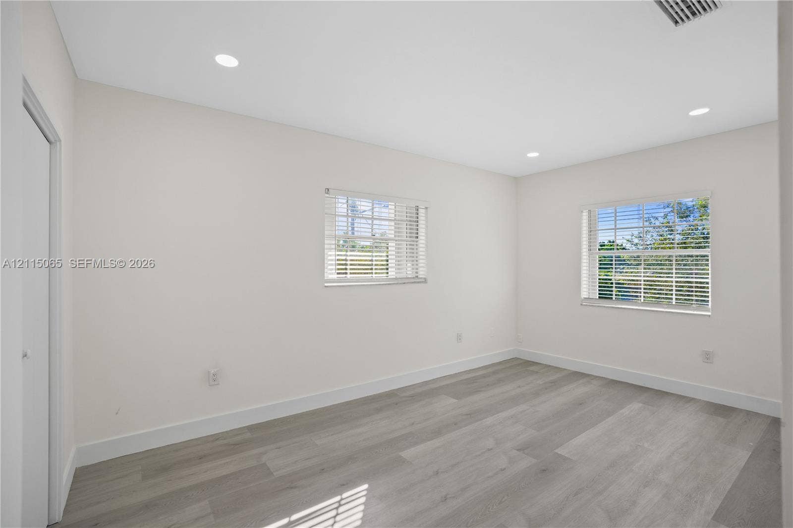 Neutral-toned interior featuring recessed lighting, wood-finish flooring, and multiple windows with horizontal blinds
