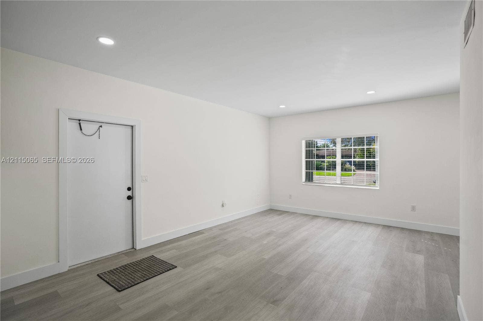 Neutral-toned wood-finish flooring, recessed lighting, and a multi-pane window