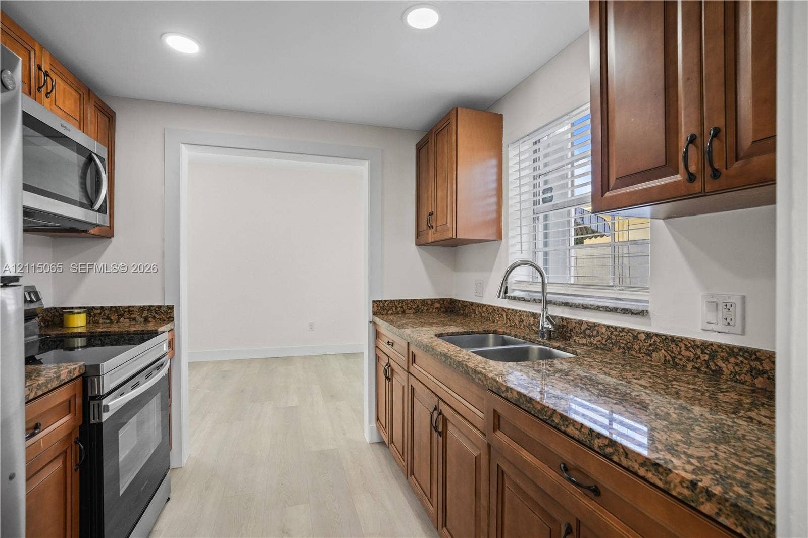 Kitchen featuring stained wood cabinetry, stone countertops, double-basin stainless steel sink, recessed lighting, and stainless steel appliances