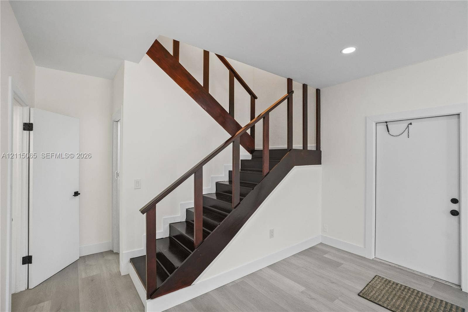 Staircase featuring dark-stained wood treads, matching wood handrails, recessed ceiling lighting, and wood-finish flooring