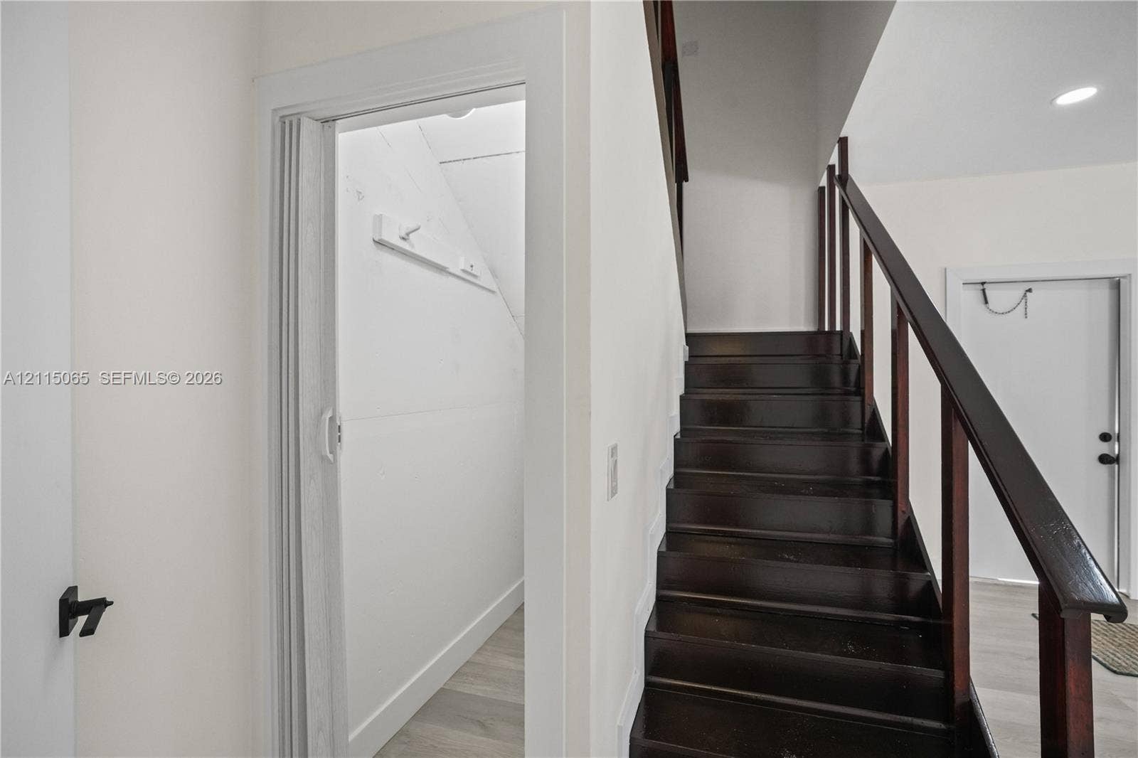 Dark wood staircase with an open-railing banister and neutral-toned wood-finish flooring