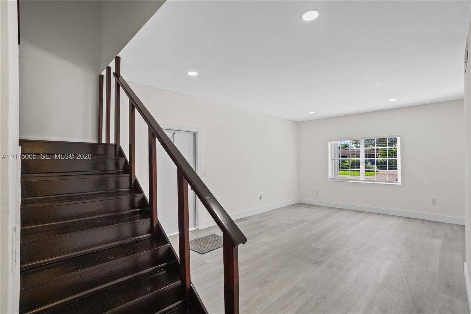 Staircase featuring dark wood-finish treads and railings, recessed ceiling lighting, and neutral wood-finish flooring throughout