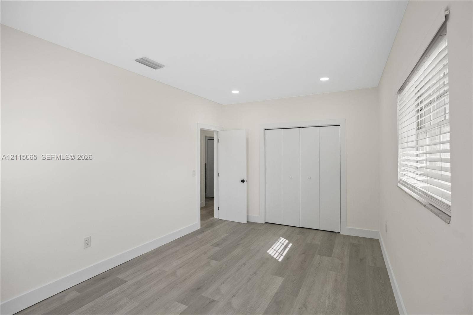 Neutral interior featuring wood-finish flooring, recessed lighting, and a closet with bifold doors