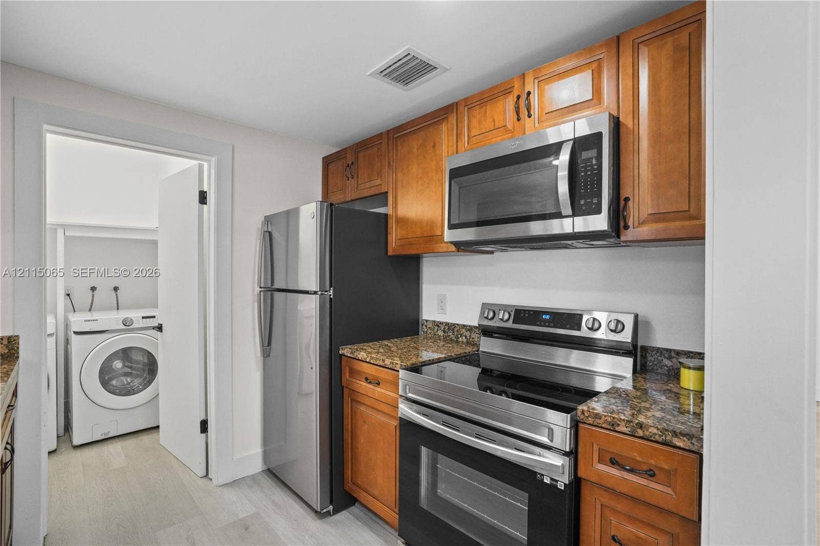 Kitchen featuring wood cabinetry, stone-finish countertops, and a stainless steel appliance suite including a built-in microwave and range