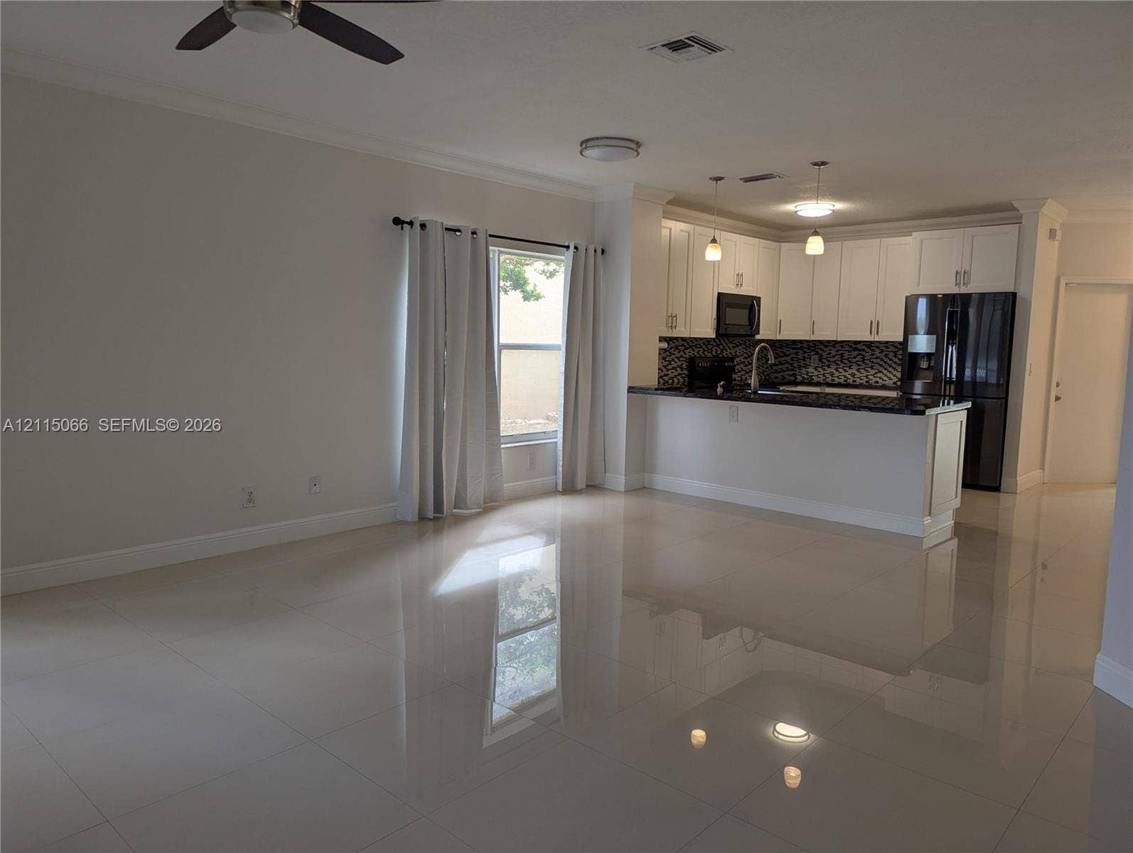 215 SW 120th Avenue, #215, Pembroke Pines, Pembroke Pines, FL 33025 Open interior space featuring polished tile flooring, white cabinetry, a kitchen peninsula with dark stone countertops, mosaic tile backsplash, and recessed and pendant lighting