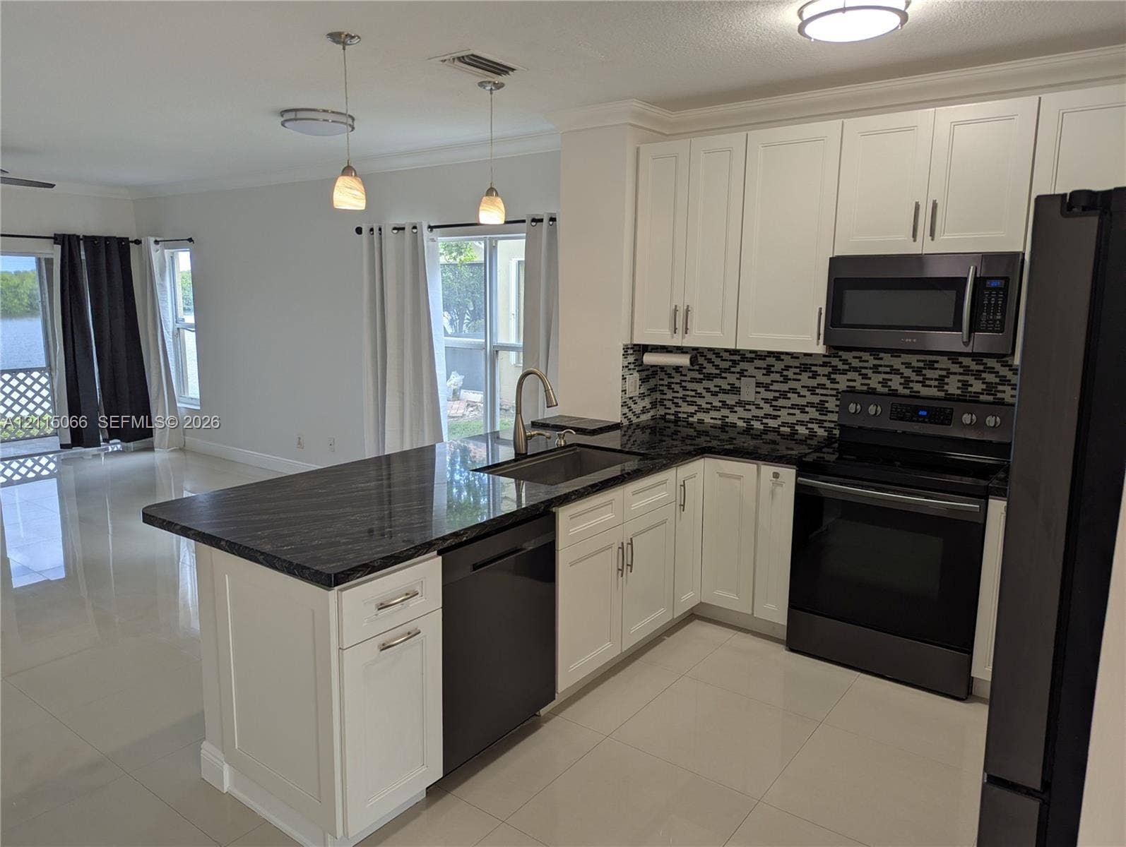 215 SW 120th Avenue, #215, Pembroke Pines, Pembroke Pines, FL 33025 Kitchen featuring white shaker-style cabinetry, dark stone countertops, a mosaic tile backsplash, stainless steel appliances, and a central island with an integrated sink