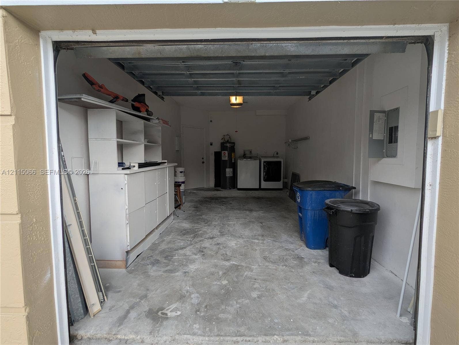 215 SW 120th Avenue, #215, Pembroke Pines, Pembroke Pines, FL 33025 Enclosed garage featuring concrete flooring, built-in white storage cabinetry, an overhead garage door, and dedicated utility connections