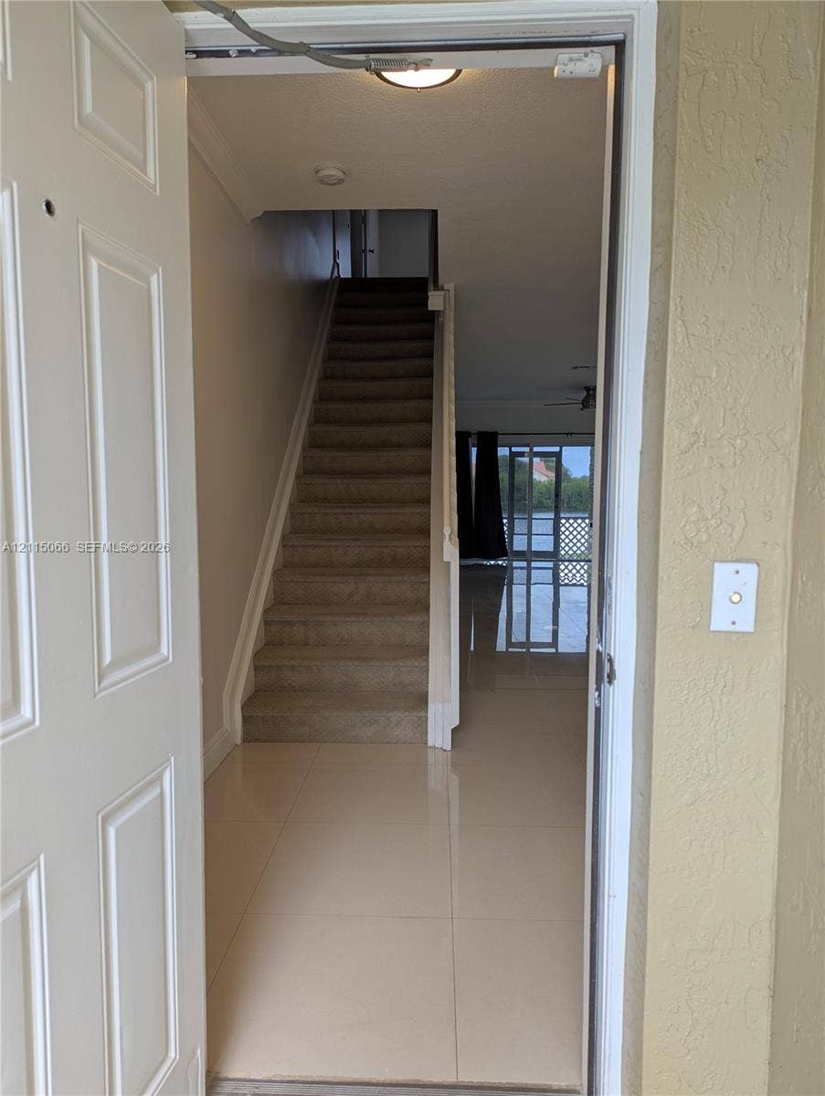 215 SW 120th Avenue, #215, Pembroke Pines, Pembroke Pines, FL 33025 Entrance featuring large-format ceramic tile flooring, a carpeted staircase with a white railing, and flush-mount ceiling lighting