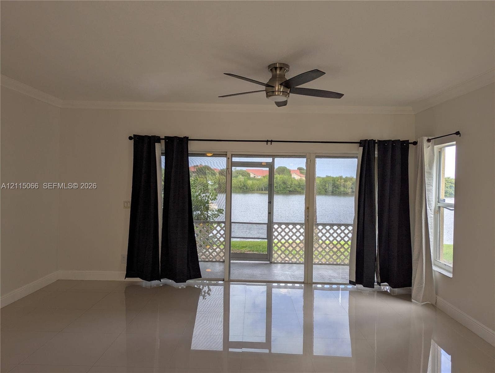 215 SW 120th Avenue, #215, Pembroke Pines, Pembroke Pines, FL 33025 Living area featuring large-format tile flooring, a brushed-nickel ceiling fan, and sliding glass doors opening to a screened-in porch with water scenery
