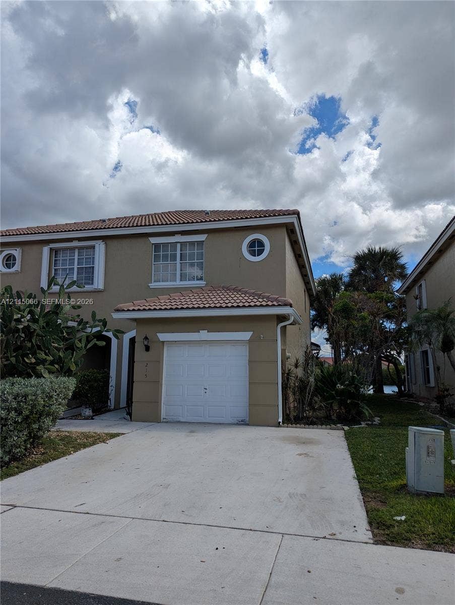 215 SW 120th Avenue, #215, Pembroke Pines, Pembroke Pines, FL 33025 Two-story exterior featuring a tile roof, single-car garage, concrete driveway, and decorative round accent windows