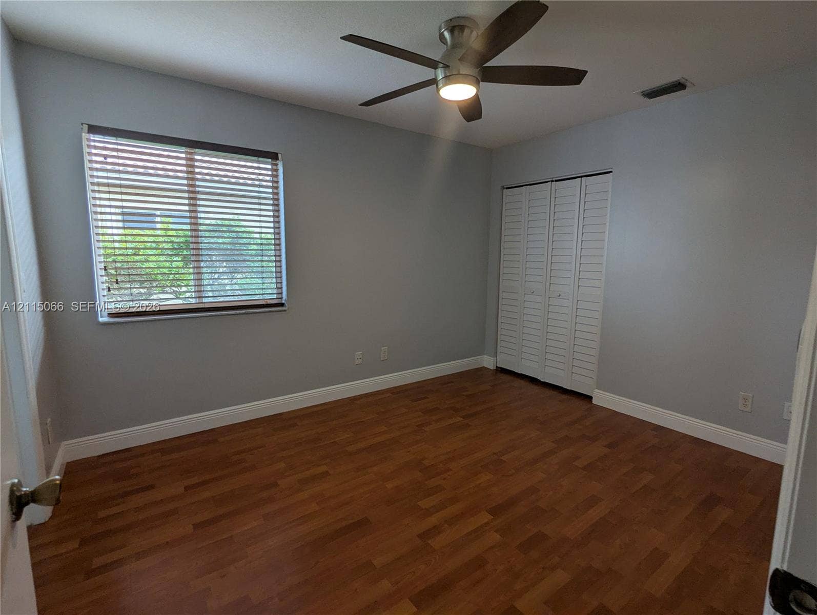 215 SW 120th Avenue, #215, Pembroke Pines, Pembroke Pines, FL 33025 Interior space featuring wood-finish flooring, a multi-blade ceiling fan with integrated lighting, and louvered bi-fold closet doors