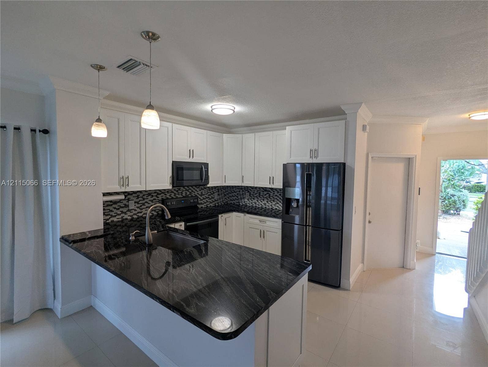215 SW 120th Avenue, #215, Pembroke Pines, Pembroke Pines, FL 33025 Kitchen featuring white shaker-style cabinetry, black stone countertops, decorative tile backsplash, dark-finish appliances, and dual pendant lighting