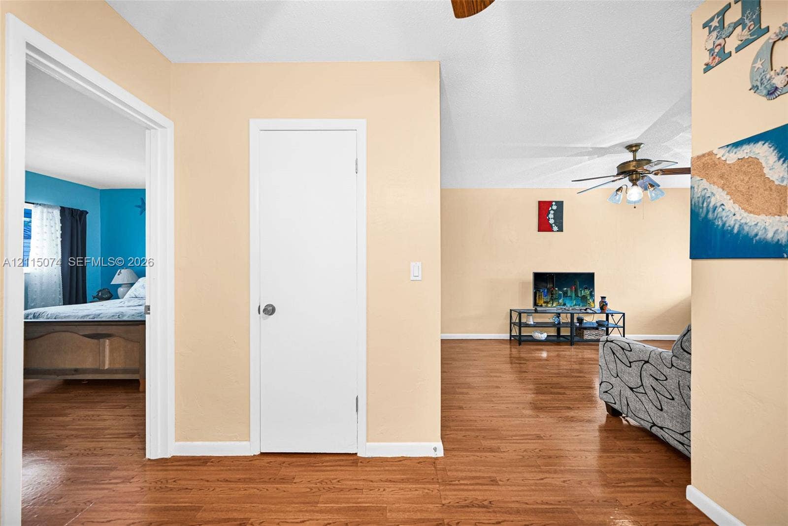 Wood-finish flooring throughout, ceiling fan with light fixture, and interior door with brushed metal hardware