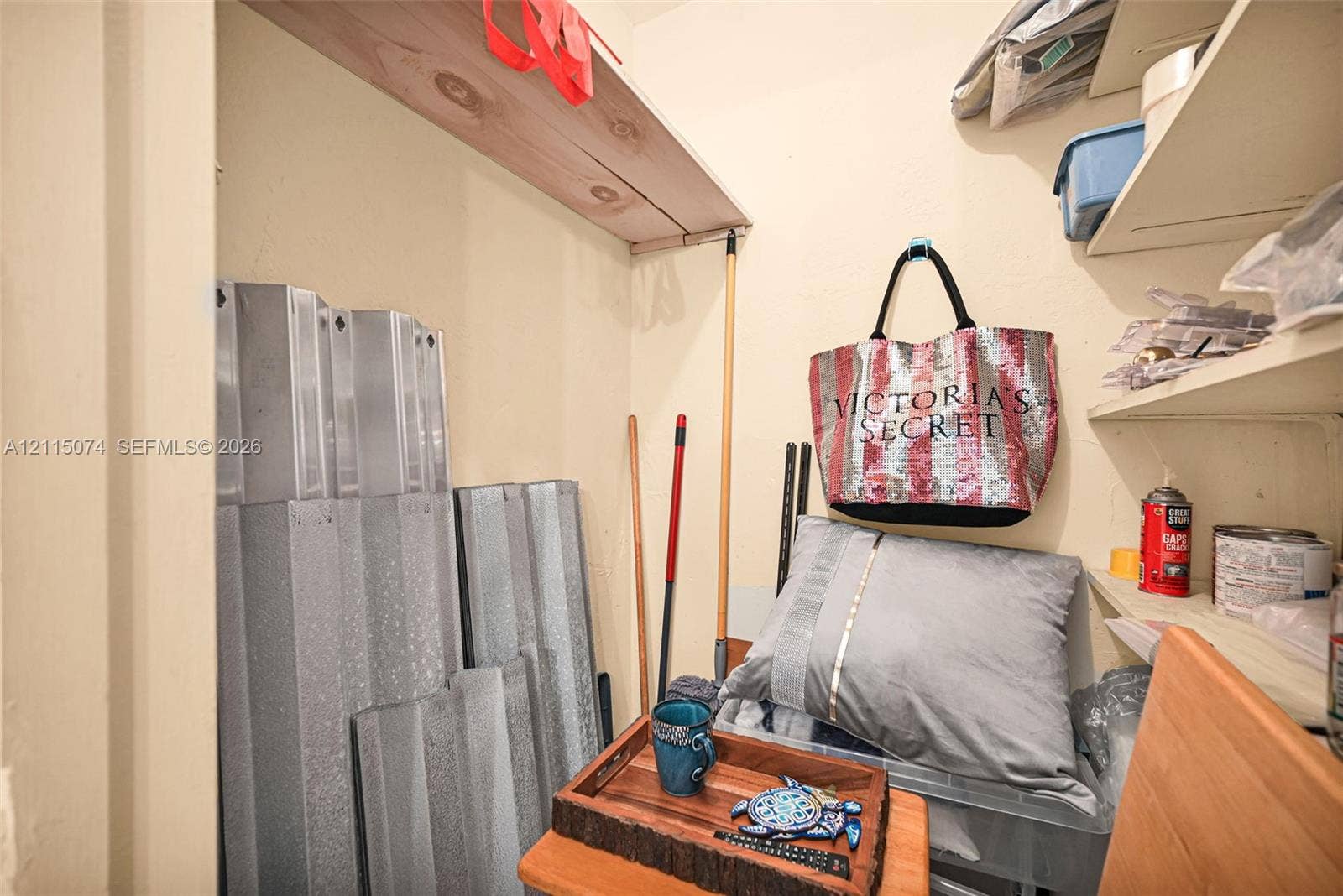 Storage closet featuring multi-tiered fixed shelving and wall-mounted storage utility hooks SHUTTERS!