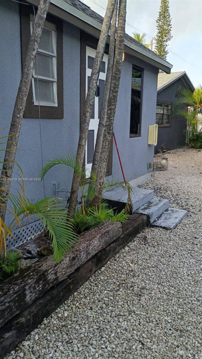 209 SW 12th Street, #A, Dania, Dania Beach, FL 33004 Exterior featuring stucco siding, timber-rail landscaping borders, concrete step entry, and gravel ground cover