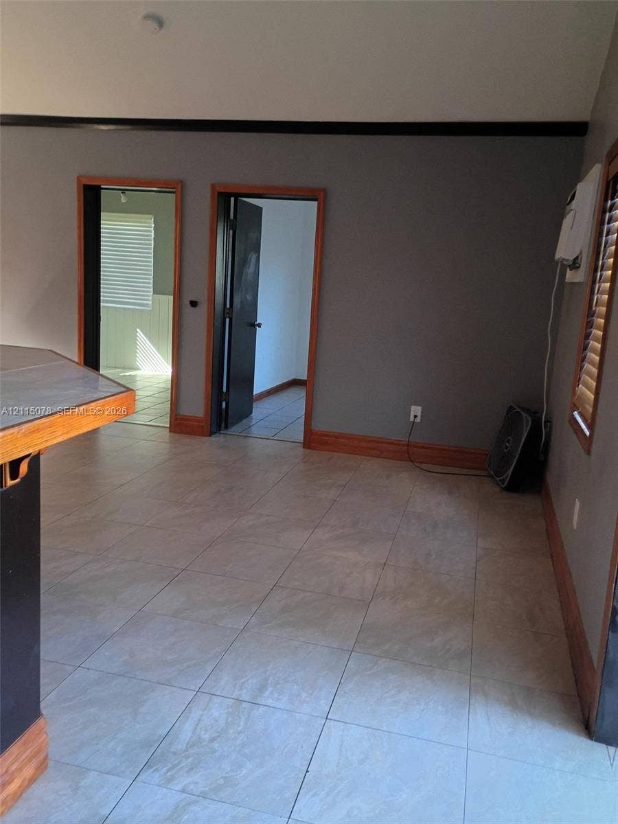 209 SW 12th Street, #A, Dania, Dania Beach, FL 33004 Interior space featuring large-format ceramic tile flooring, wood-toned door casing and trim, and wall-mounted window air conditioning unit