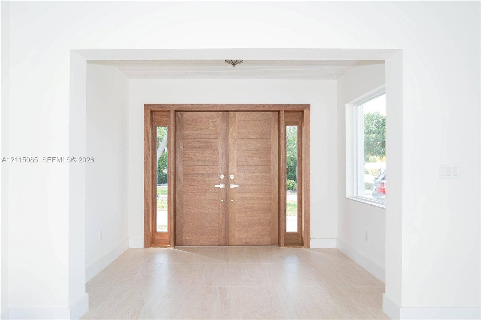 663 Woodcrest Road, Key Biscayne, Key Biscayne, FL 33149 Double entry doors featuring wood-grain finish, integrated sidelights, and brushed metallic hardware, complemented by light-toned porcelain tile flooring
