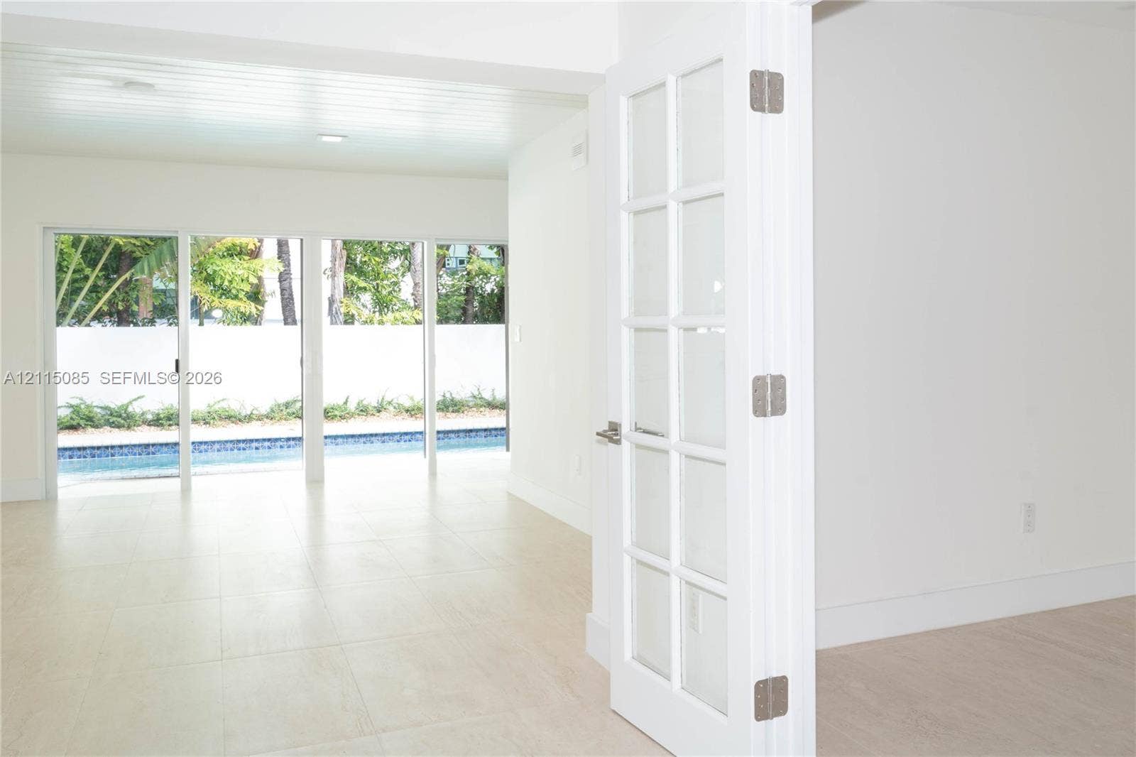 663 Woodcrest Road, Key Biscayne, Key Biscayne, FL 33149 Interior space featuring light-toned porcelain tile flooring, multi-panel glass sliding doors, and a French door with glass inserts