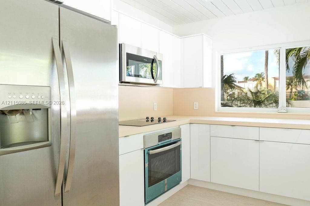 663 Woodcrest Road, Key Biscayne, Key Biscayne, FL 33149 Kitchen featuring white cabinetry, stainless steel appliances, solid surface countertops, and a built-in cooktop