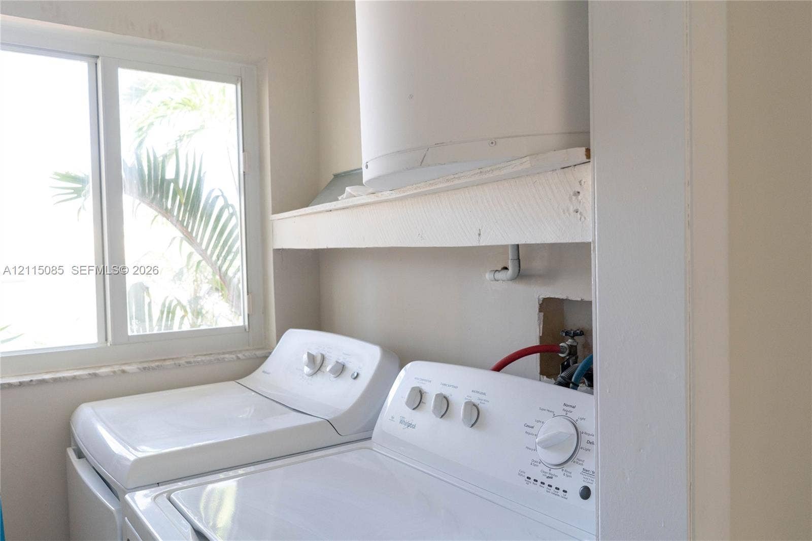 663 Woodcrest Road, Key Biscayne, Key Biscayne, FL 33149 Laundry area featuring white top-load washer and dryer, horizontal built-in shelving, and a large sliding window with stone-finish sill