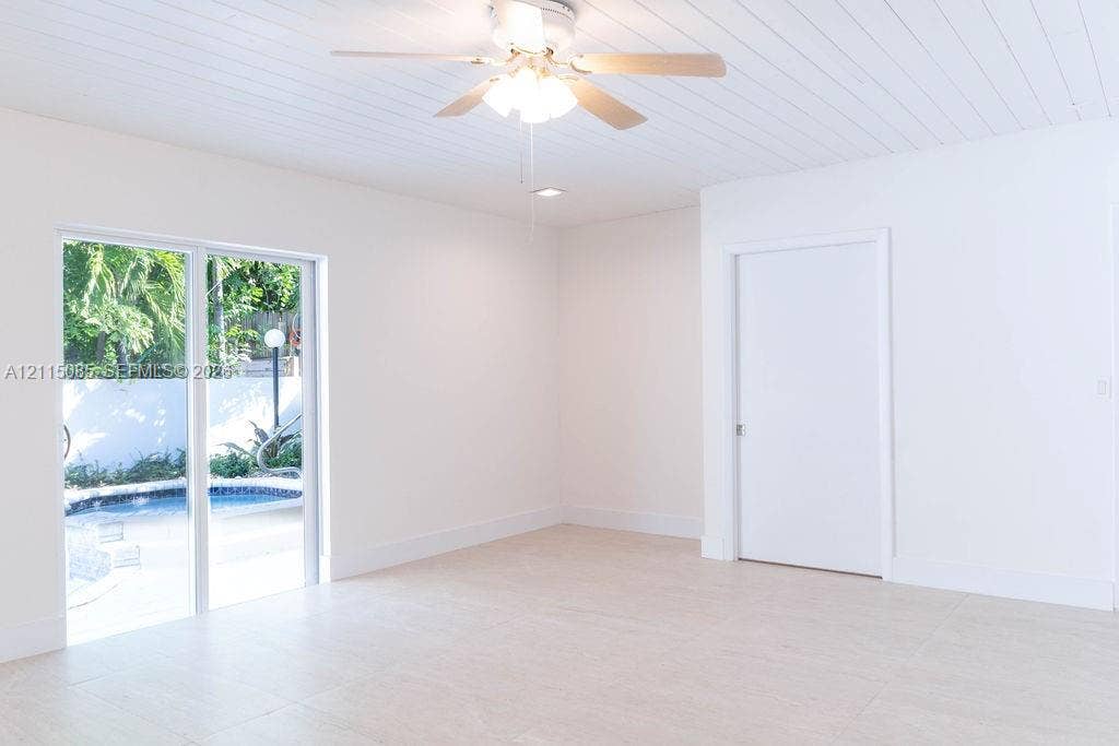 663 Woodcrest Road, Key Biscayne, Key Biscayne, FL 33149 Interior space featuring light-toned porcelain tile flooring, beadboard ceiling, ceiling fan with integrated lighting, and sliding glass door with exterior pool access