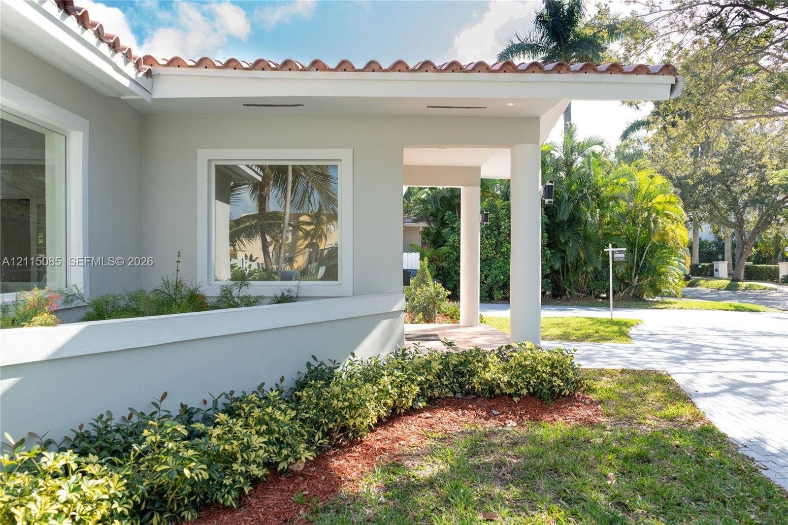 663 Woodcrest Road, Key Biscayne, Key Biscayne, FL 33149 Exterior facade featuring terracotta roof tiles, smooth stucco finish, recessed lighting, and a covered entryway supported by circular columns