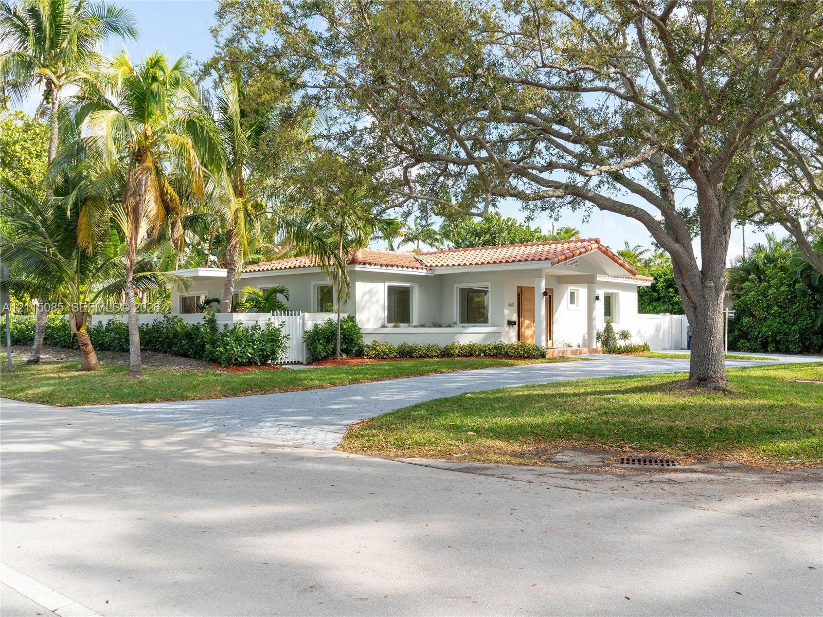 663 Woodcrest Road, Key Biscayne, Key Biscayne, FL 33149 Single-story residence featuring a tile roof, paved driveway, enclosed perimeter wall, and mature landscaping