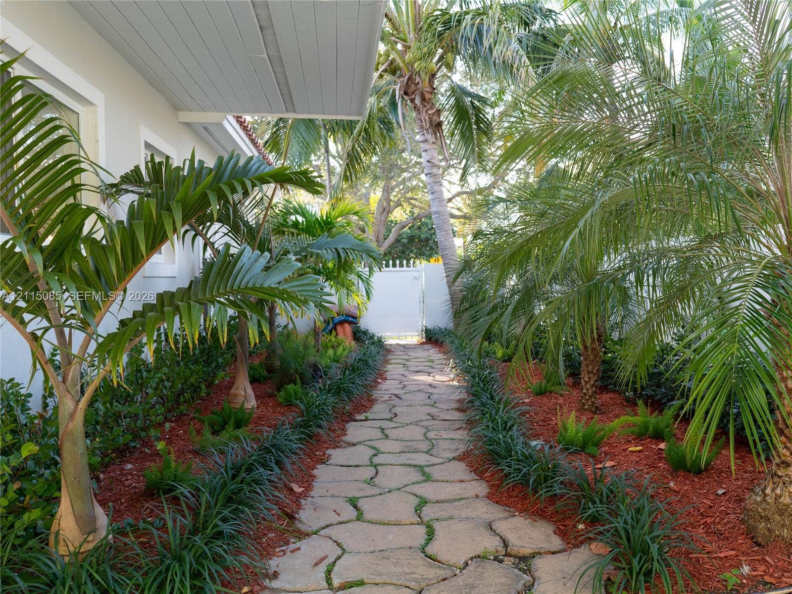 663 Woodcrest Road, Key Biscayne, Key Biscayne, FL 33149 Flagstone walkway bordered by mature palm trees and manicured landscape beds with red mulch