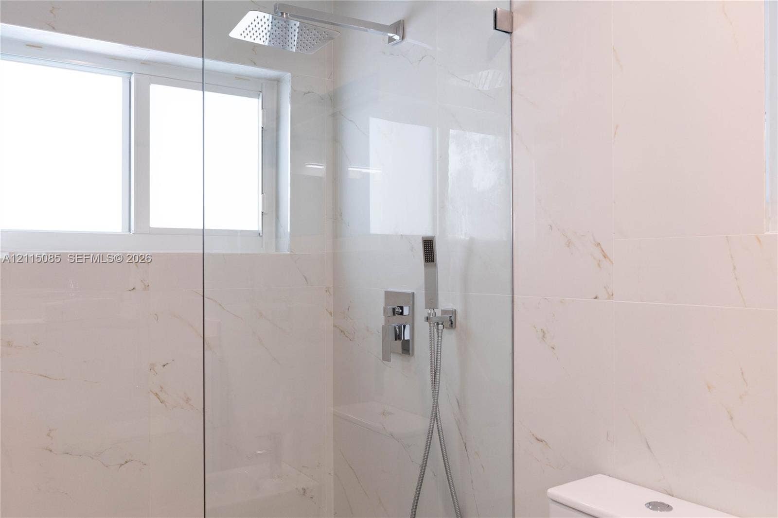 663 Woodcrest Road, Key Biscayne, Key Biscayne, FL 33149 Walk-in shower featuring large-format stone-finish wall tile, frameless glass enclosure, rainfall showerhead, handheld shower wand, and integrated chrome fixtures