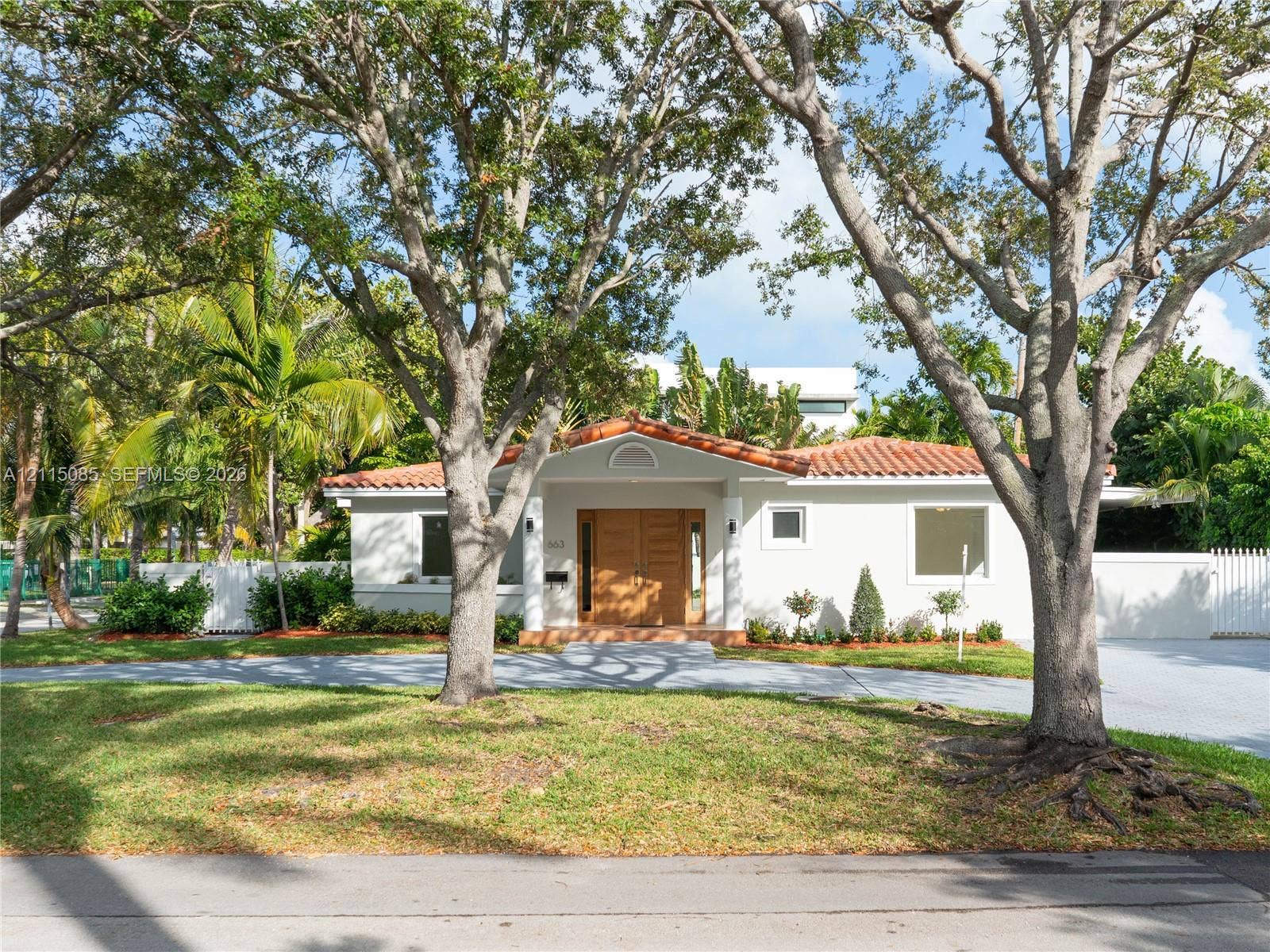 663 Woodcrest Road, Key Biscayne, Key Biscayne, FL 33149 Stucco exterior featuring a terracotta tile roof, wood-finish double front doors, and a paver driveway