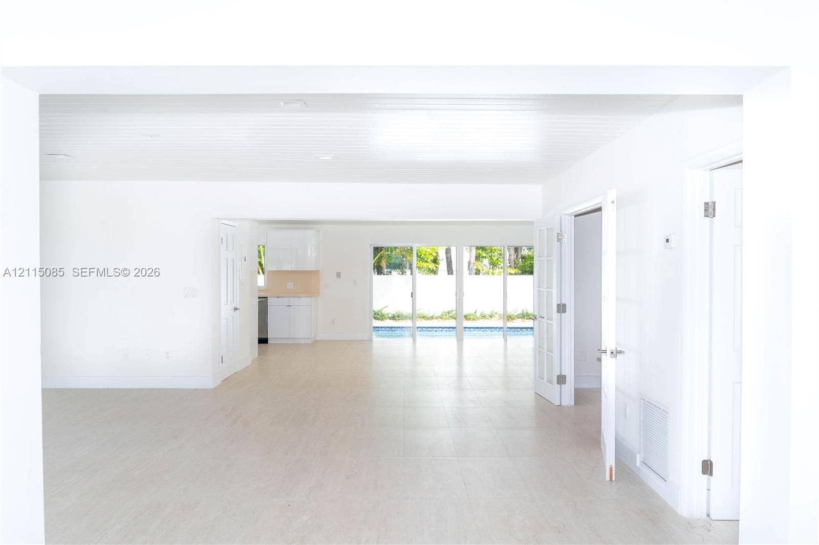 663 Woodcrest Road, Key Biscayne, Key Biscayne, FL 33149 Open-concept interior featuring light-toned porcelain tile flooring, recessed ceiling lighting, glass sliding doors, and white cabinetry
