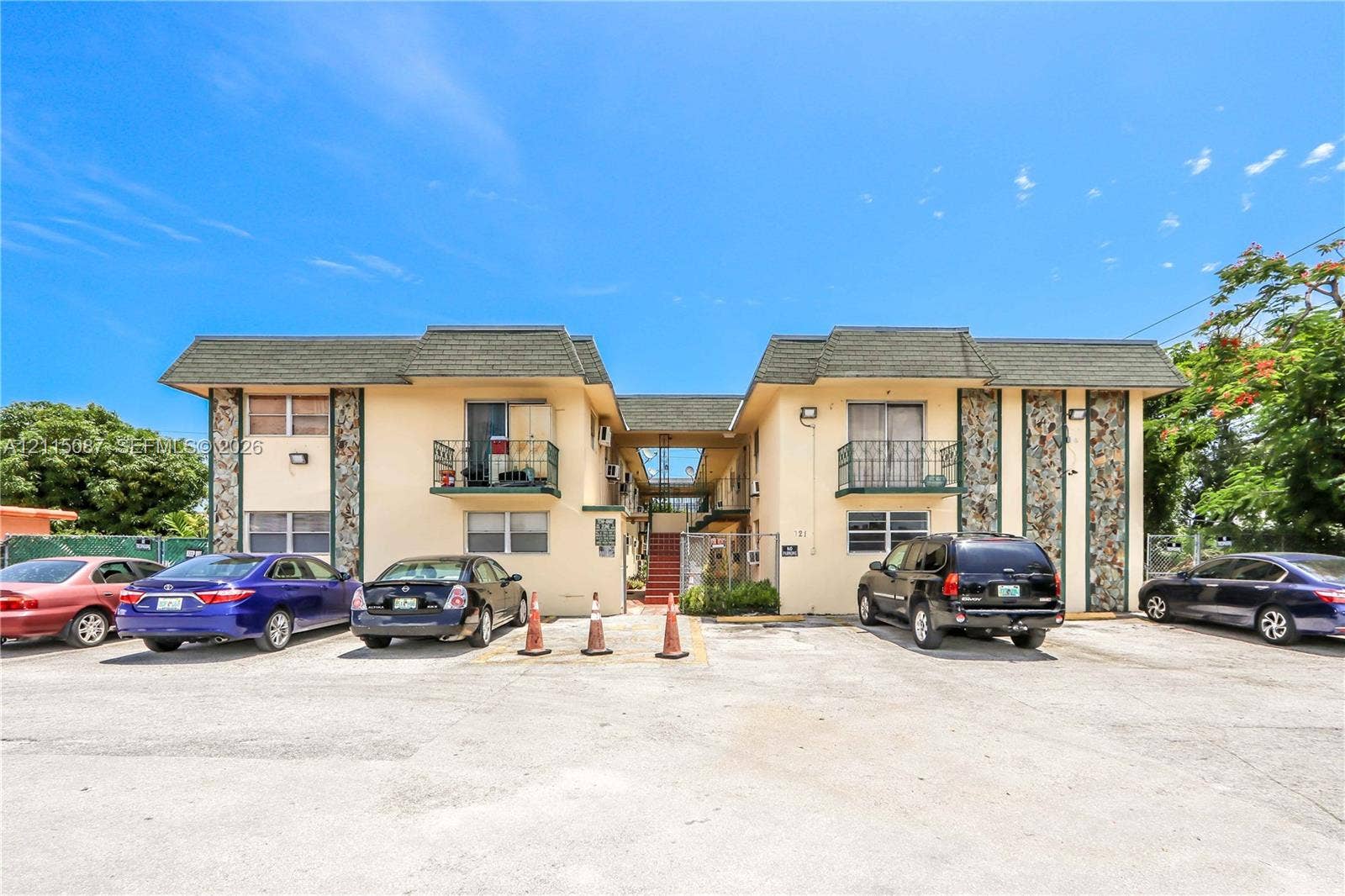 720 NW 27th Court, #18, Miami, Miami, FL 33125 Two-story exterior featuring a shingled mansard roof, stucco facade, stone-textured vertical accent panels, and wrought iron balcony railings