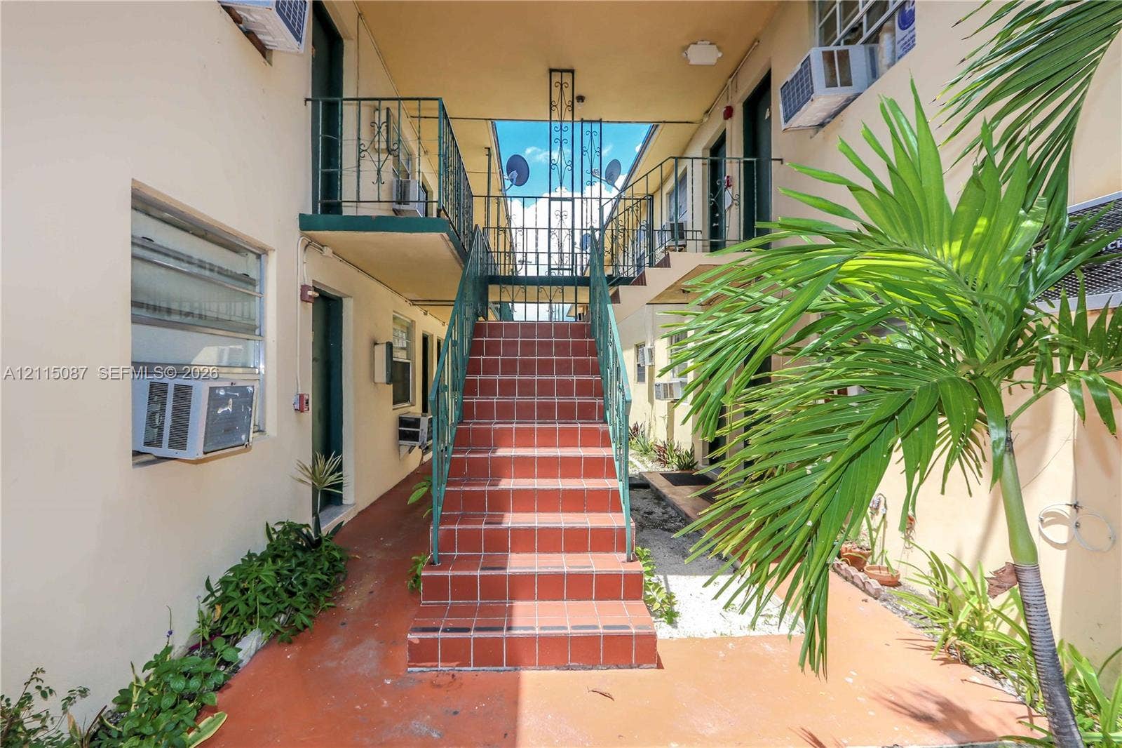 720 NW 27th Court, #18, Miami, Miami, FL 33125 Exterior staircase featuring tile treads and metal railings, flanked by second-level metal balcony walkways and stucco wall construction