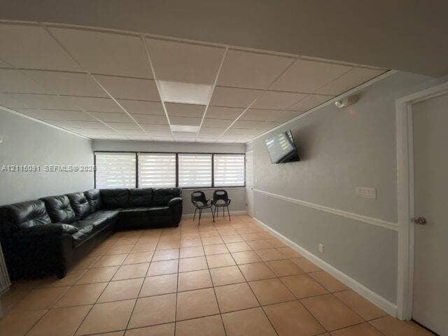7715 SW 86th Street, #A2-402, Miami, Miami, FL 33143 Interior space featuring ceramic tile flooring, a grid-patterned drop ceiling, and large windows with horizontal blinds