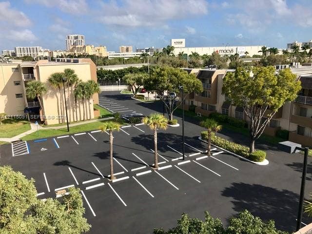 7715 SW 86th Street, #A2-402, Miami, Miami, FL 33143 Paved surface parking lot featuring marked stalls, designated accessible parking spaces, and mature palm and shade trees