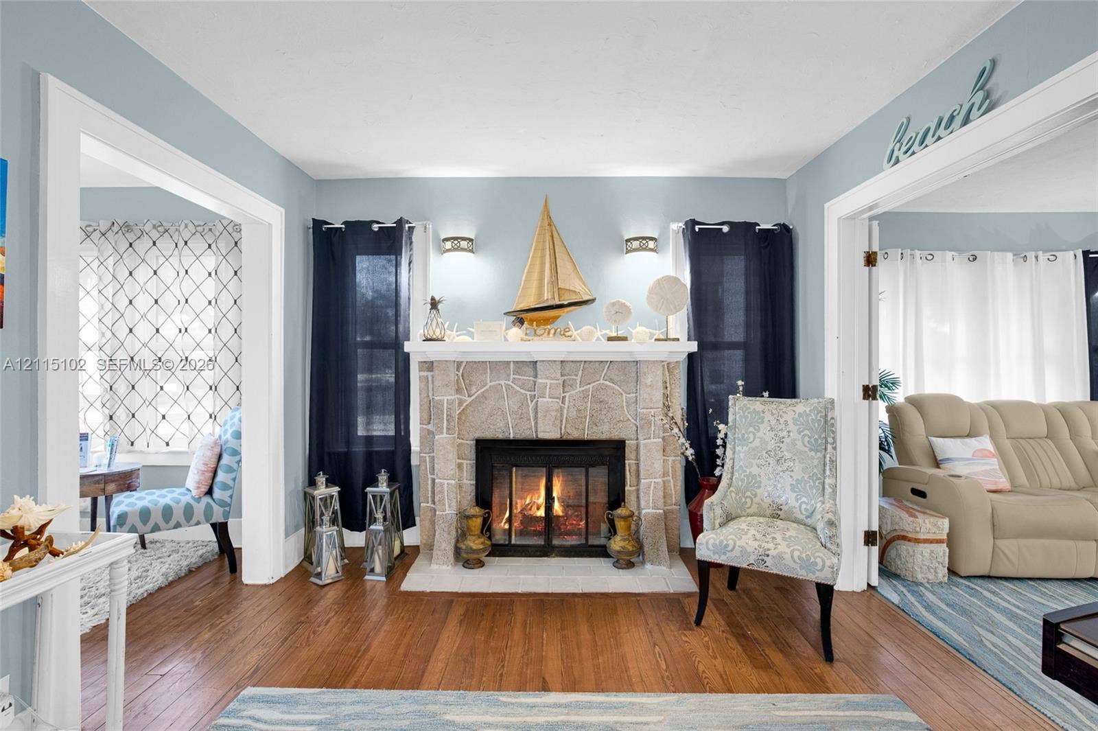 110 S Peninsula, New Smyrna Beach, FL 32169 Stone fireplace surround with a wood mantle, wood-finish flooring, and wall-mounted light fixtures