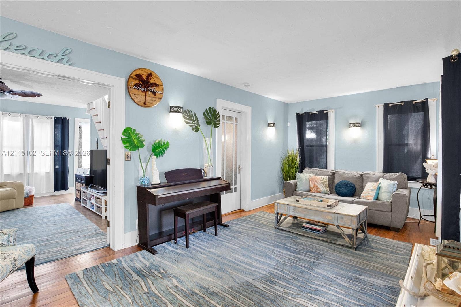 110 S Peninsula, New Smyrna Beach, FL 32169 Living space featuring wood-finish flooring, white door and window casings, multiple wall-mounted light fixtures, and a glass-panel door