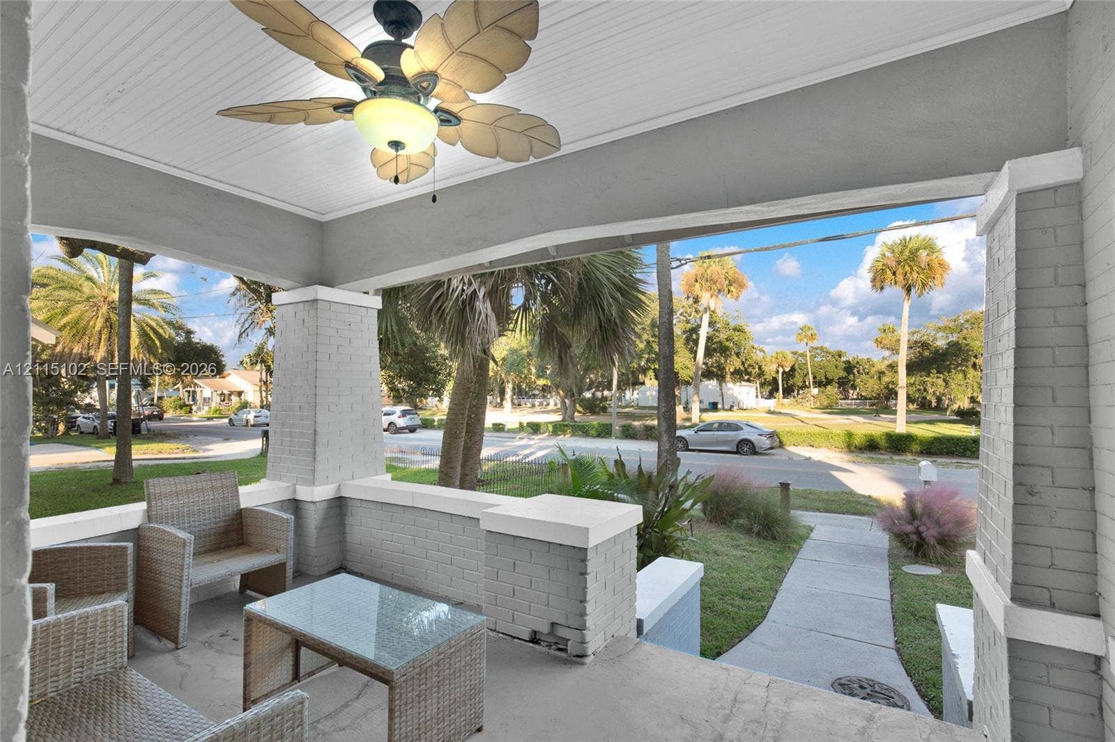 110 S Peninsula, New Smyrna Beach, FL 32169 Covered front porch featuring a painted brick foundation, concrete flooring, beaded-board ceiling, and a palm-leaf blade ceiling fan
