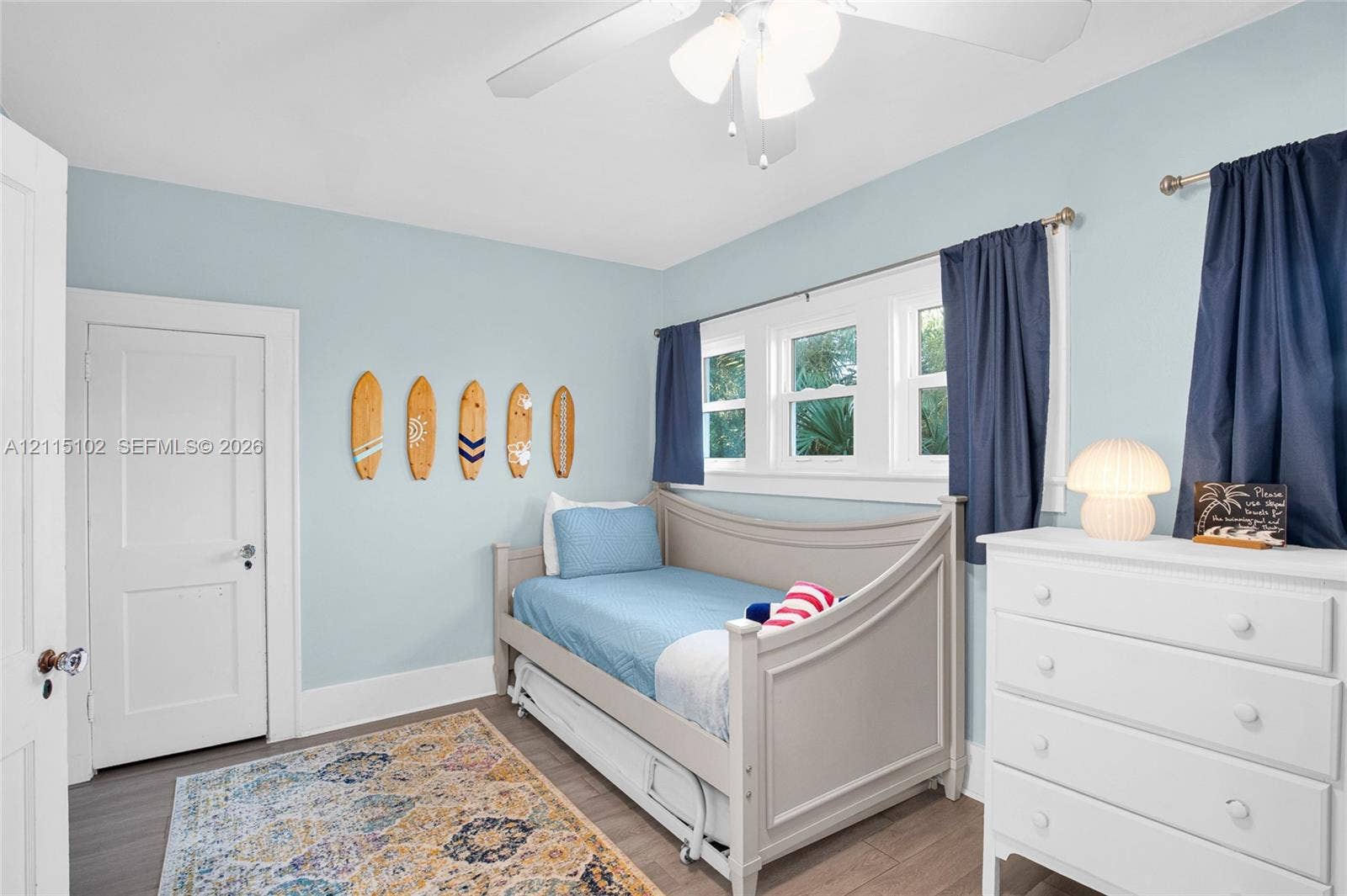 110 S Peninsula, New Smyrna Beach, FL 32169 Neutral-toned wall paint, wood-finish flooring, multi-pane window configuration, and three-blade ceiling fan with integrated lighting