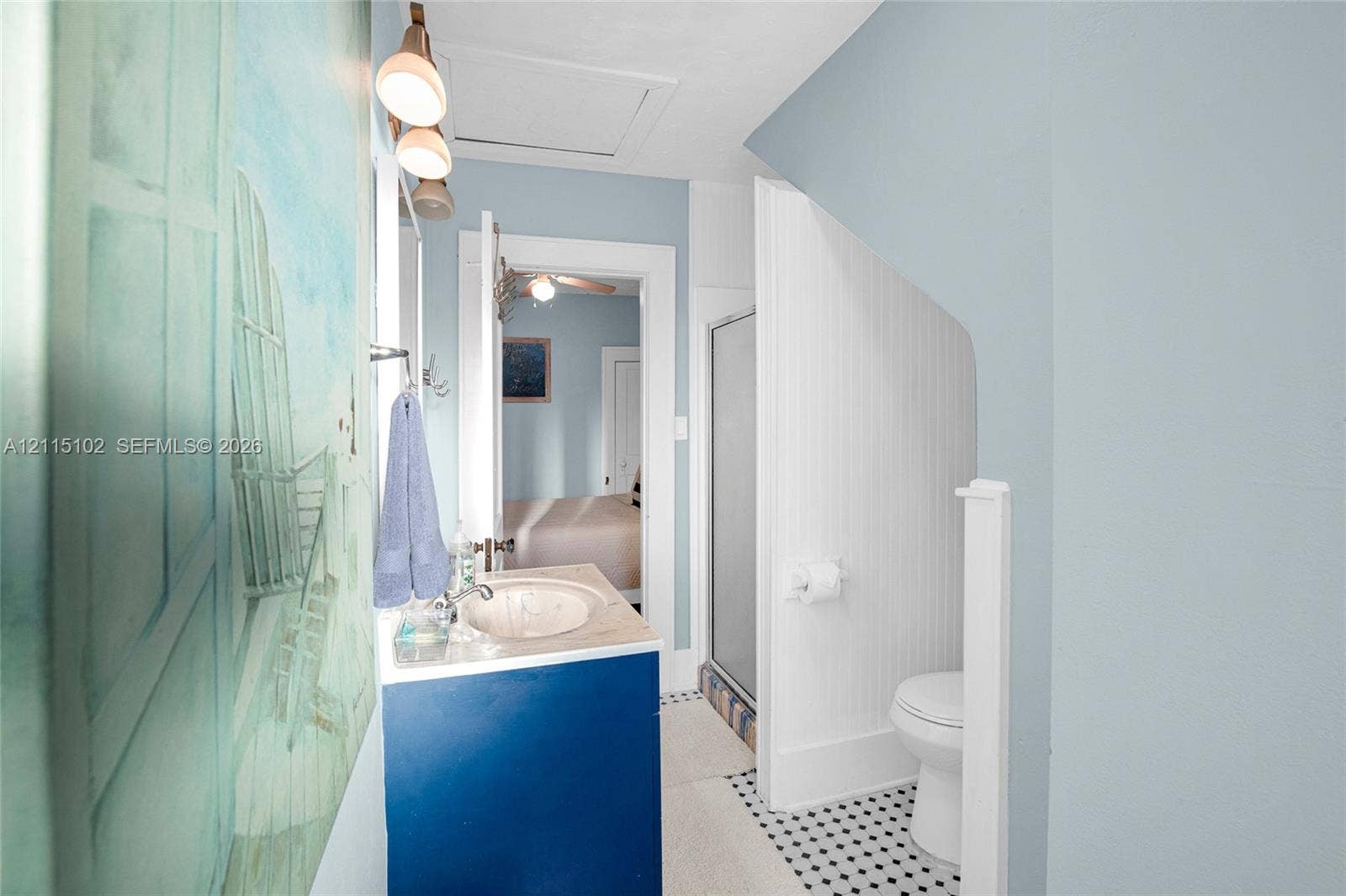 110 S Peninsula, New Smyrna Beach, FL 32169 Bathroom featuring a vanity with an integrated sink, beadboard wall paneling, a glass-enclosed shower, and geometric patterned tile flooring