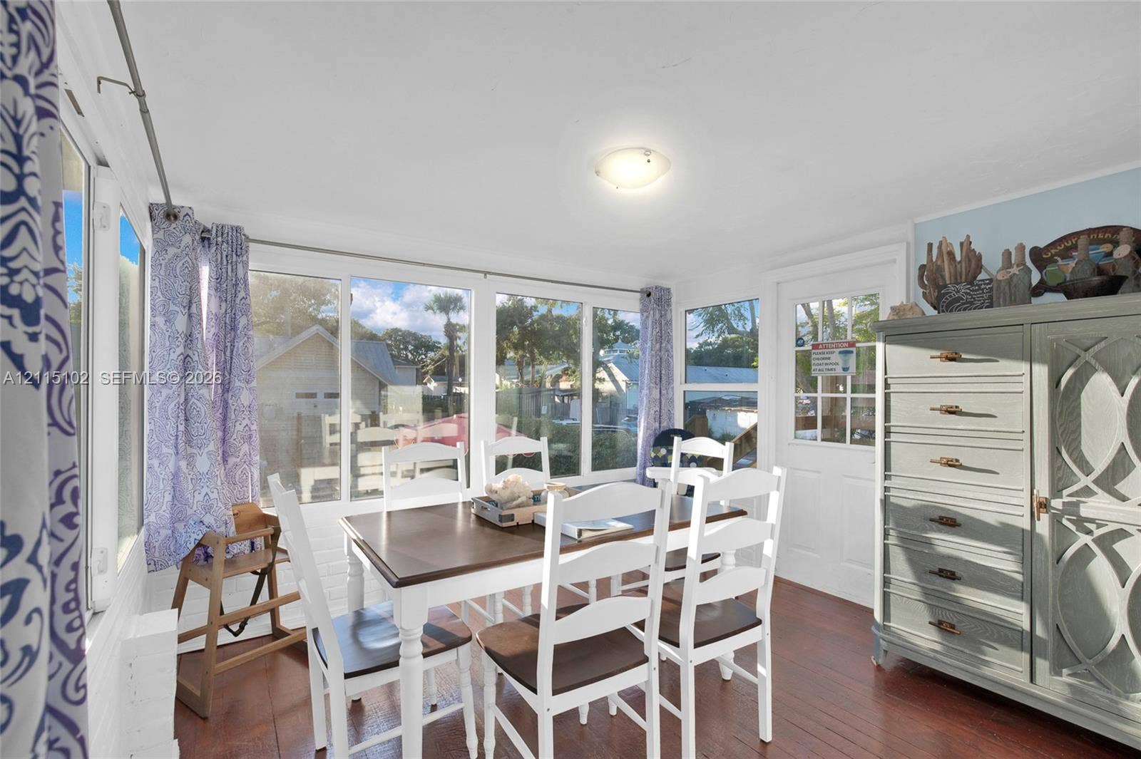 110 S Peninsula, New Smyrna Beach, FL 32169 Sunroom featuring multiple large windows, wood-finish flooring, and a multi-pane glass-panel entry door