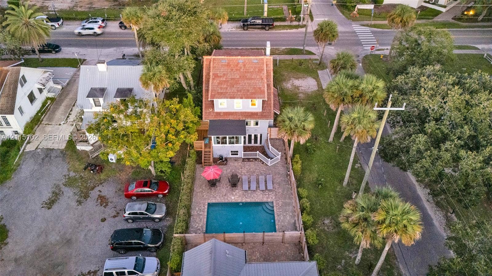 110 S Peninsula, New Smyrna Beach, FL 32169 Aerial perspective of a multi-story residence featuring a shingled roof, a paved patio, an in-ground swimming pool, and mature palm trees