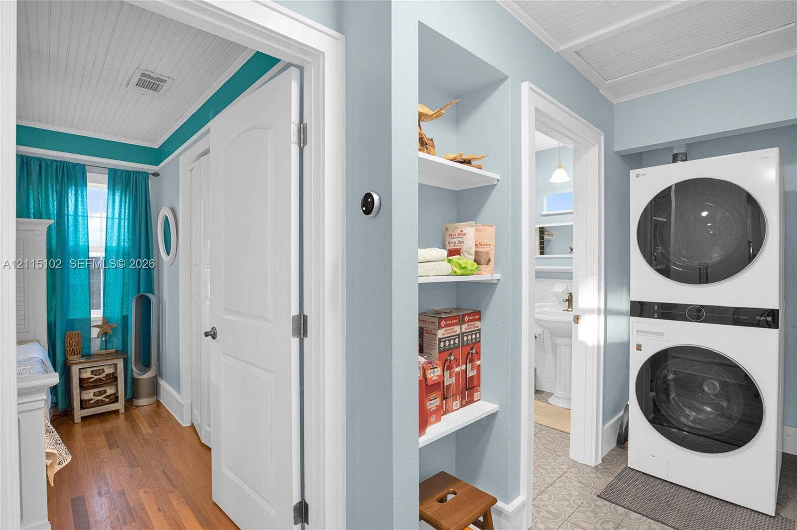 110 S Peninsula, New Smyrna Beach, FL 32169 Laundry area featuring stacked washer and dryer, beadboard ceiling, built-in shelving, wood-finish flooring, and tile flooring