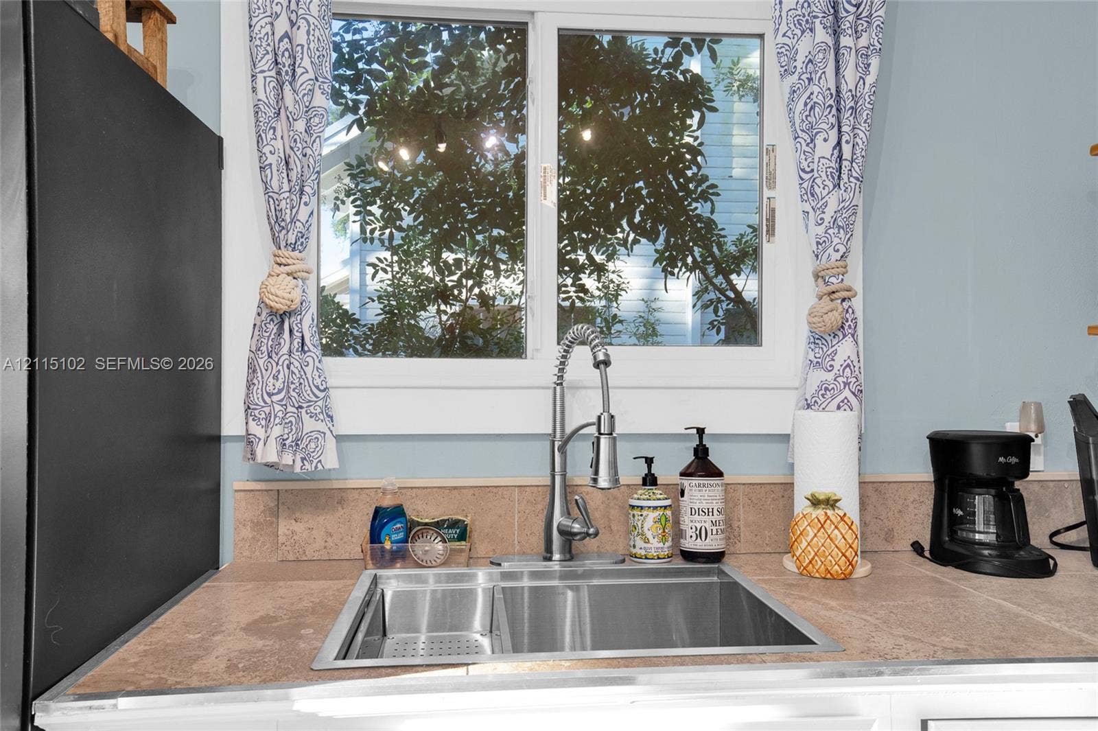 110 S Peninsula, New Smyrna Beach, FL 32169 Stainless steel dual-basin undermount sink featuring a high-arc pull-down faucet and tile countertop