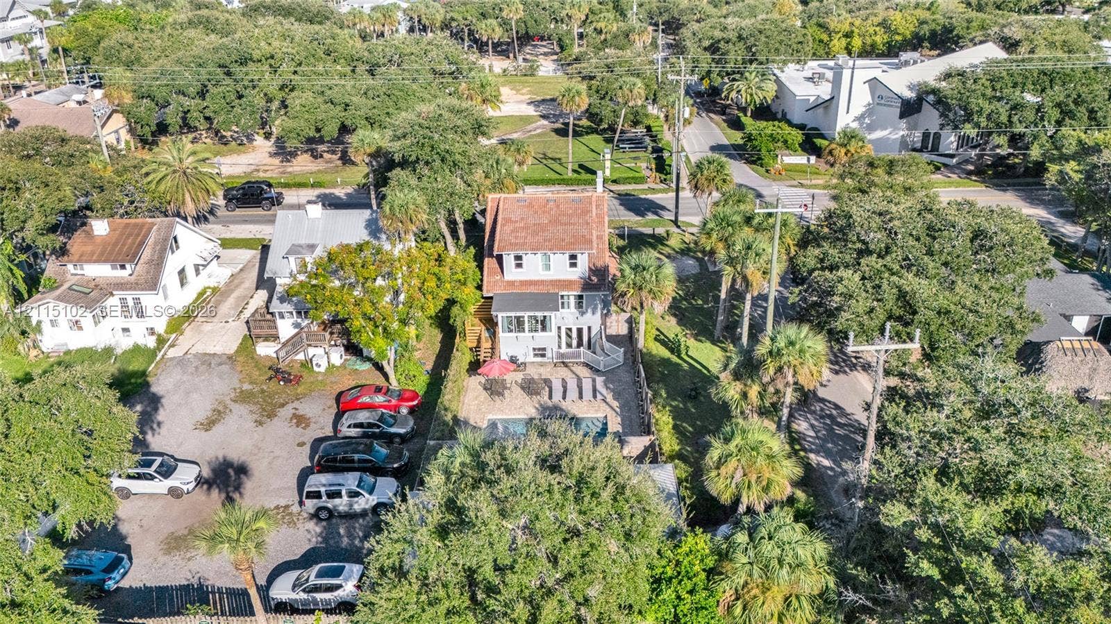 110 S Peninsula, New Smyrna Beach, FL 32169 Aerial perspective featuring a multi-story residence with a pitched roof, an in-ground swimming pool, a stone-surfaced patio area, and mature canopy trees