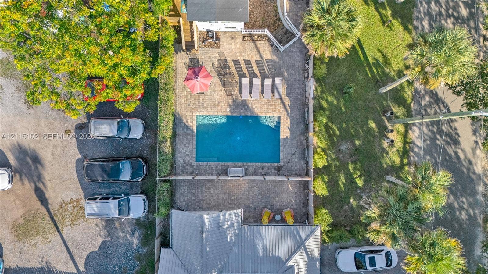 110 S Peninsula, New Smyrna Beach, FL 32169 Aerial perspective of an outdoor space featuring a rectangular in-ground swimming pool, stone paver decking, and mature palm trees