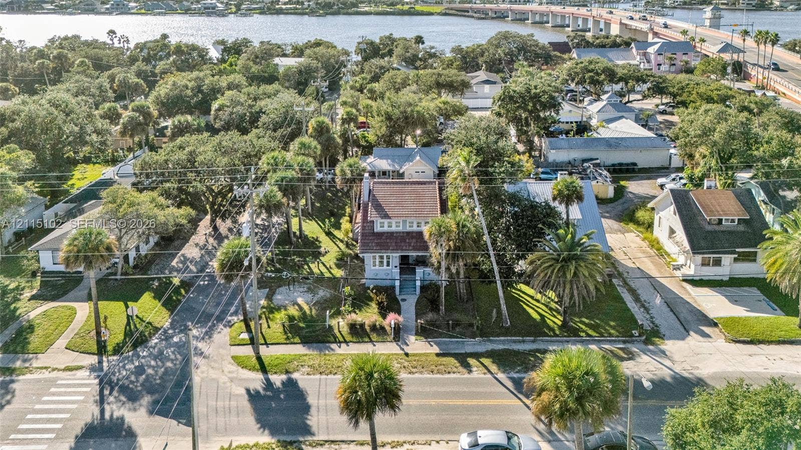 110 S Peninsula, New Smyrna Beach, FL 32169 Aerial perspective of a multi-story residence featuring a shingled roof, exterior chimney, mature landscaping, and palm trees