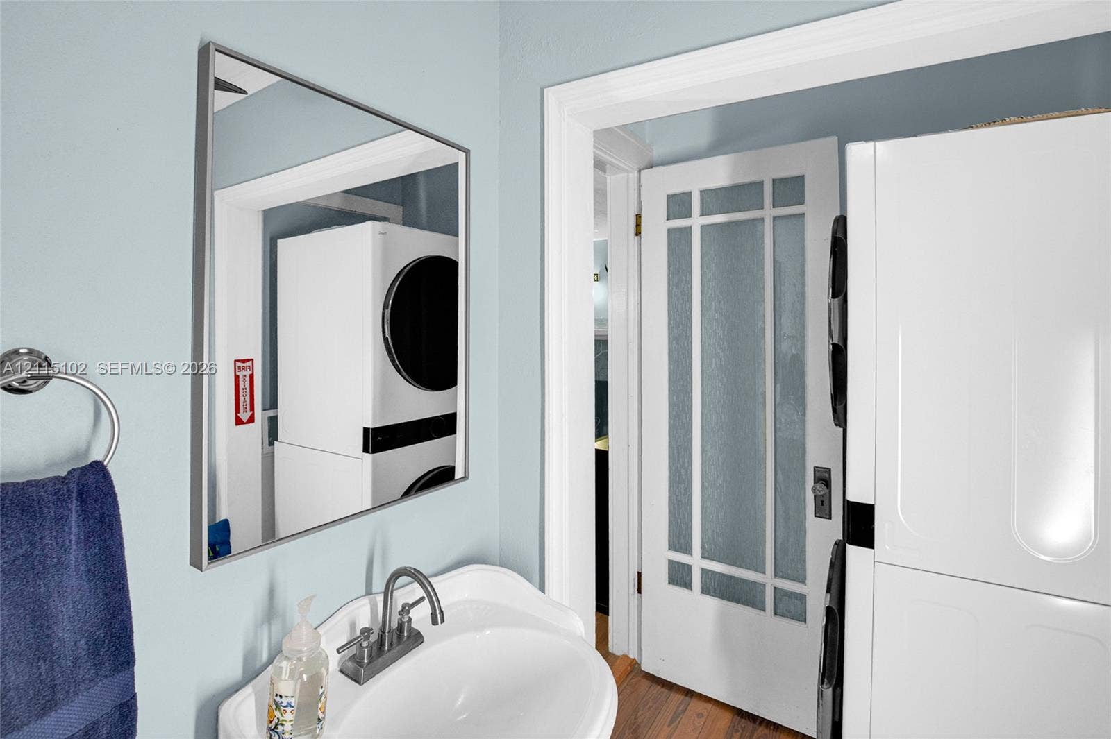110 S Peninsula, New Smyrna Beach, FL 32169 Pedestal sink with chrome-finish faucet, rectangular wall-mounted mirror, and white door featuring glass panels