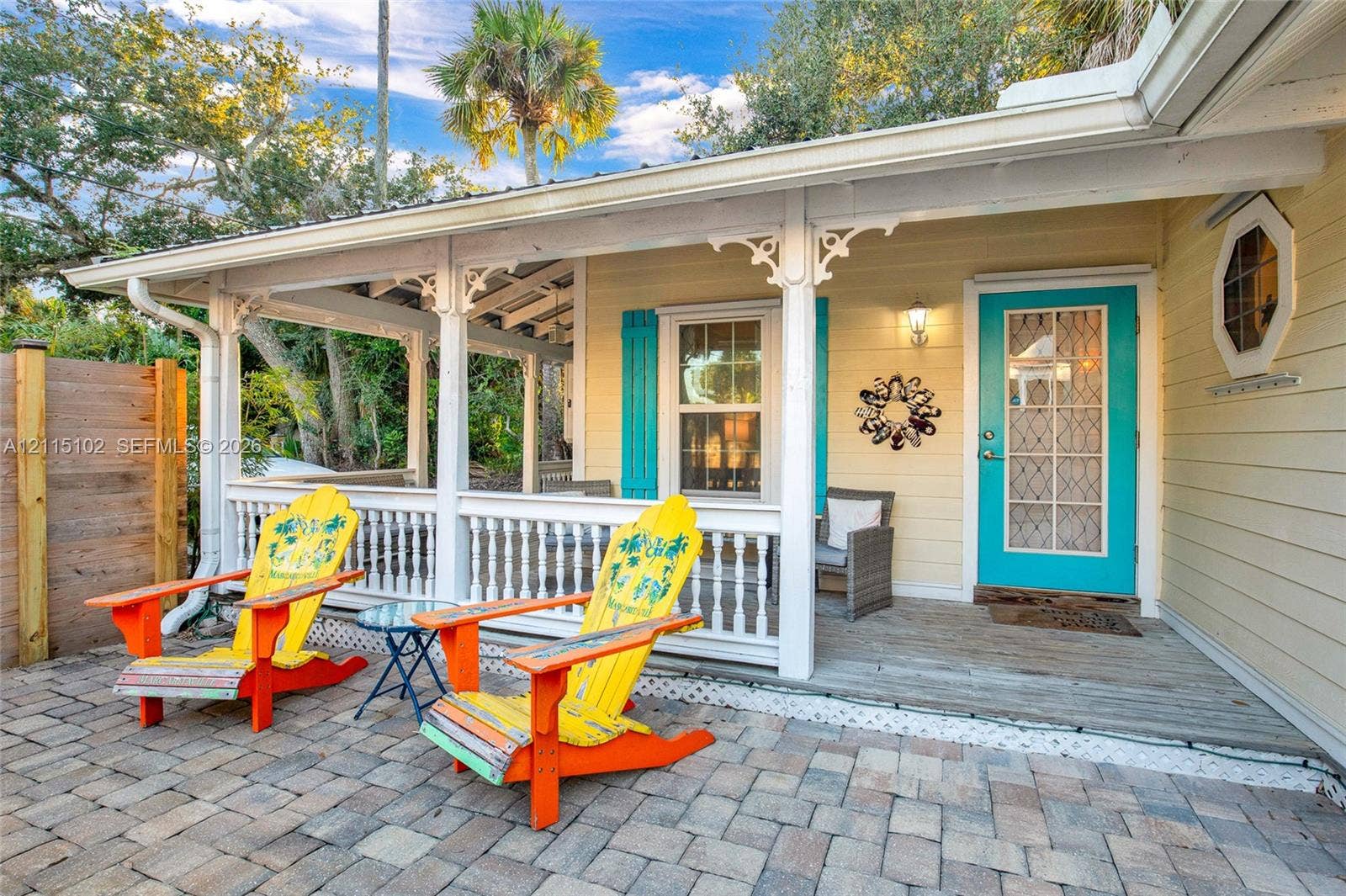 110 S Peninsula, New Smyrna Beach, FL 32169 Covered porch featuring intricate gingerbread trim, horizontal lap siding, a paneled front door with divided-light glass, and a stone-paver patio