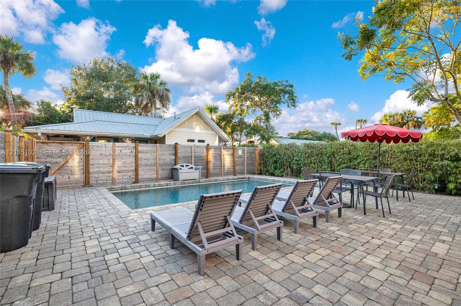 110 S Peninsula, New Smyrna Beach, FL 32169 Rectangular in-ground pool featuring a paver patio, wood-slat privacy fencing, and mature perimeter landscaping